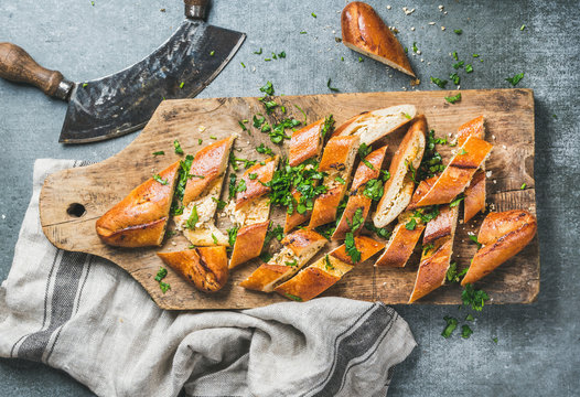 Turkish oriental pizza pide with cheese and spinach chopped in slices on wooden board over grey stone background, top view