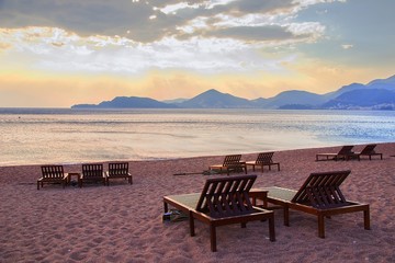 Fototapeta na wymiar Chairs on sandy beach resort in cape St.Stefan, Montenegro.