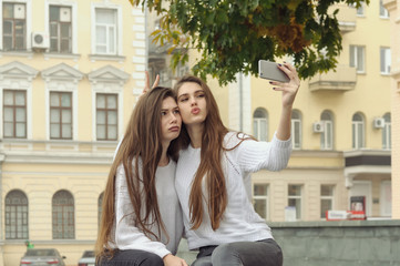 Two brunettes are curled in front of the smartphone