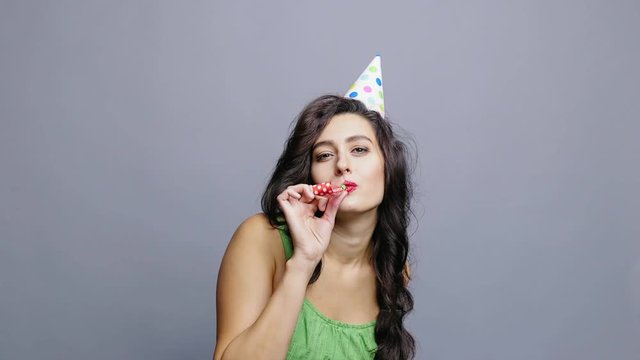 Young woman with party horn in party hat slow motion