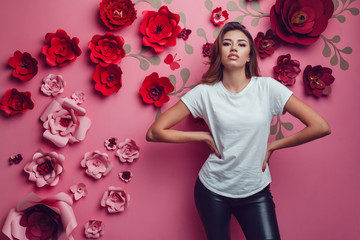Sexy woman in a white t-shirt on a pink background with flowers.