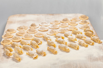 Homemade Ravioli with flour on big wooden board.