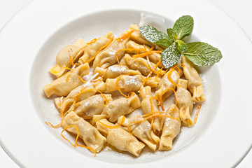 Close-up of the plate of ravioli with grated orange peel and a mint leaf.