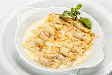 Close-up of the bowl of ravioli bowl of ravioli in white sauce with grated orange peel.