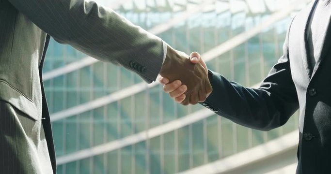 Two businessmen, just concluded a job contract, are shaking hands with their success in the economic and financial sphere. Concept of: team, business, success.