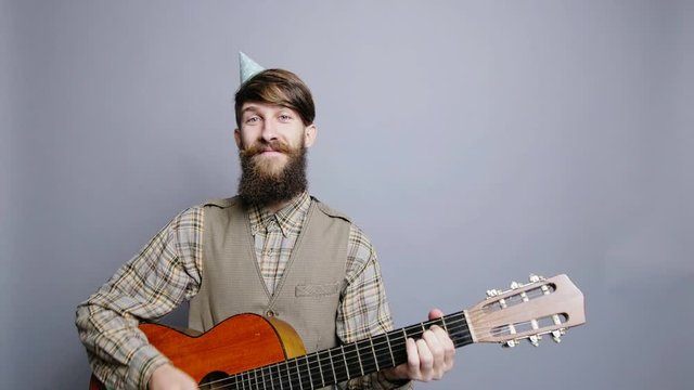 Bearded man with guitar and party hat concept patry and birthday celebration