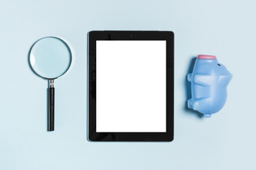 tablet pc with magnifier, coin bank on the blue background.