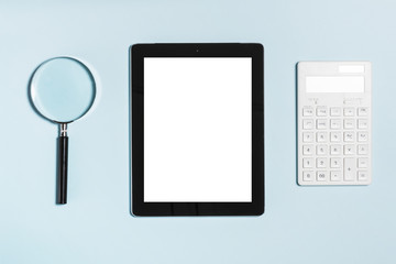 tablet pc with magnifier, calculator on the blue background.