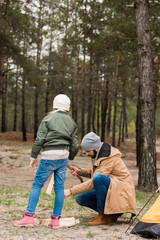 father and daughter preparing logs for campfire