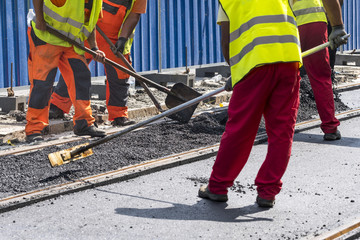 Workers construct asphalt road and railroad lines