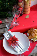 Christmas table with red tablecloth, plates and glasses on it