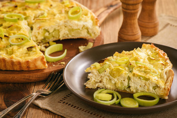 Quiche with leek and cheese on brown background.