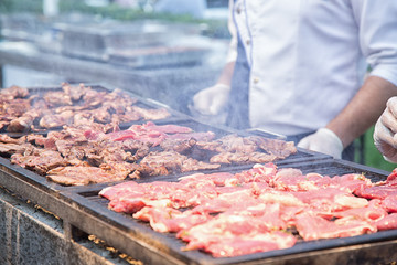 Man grilling meat on barbecue grill.