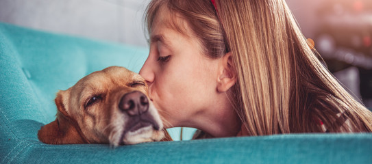 Little girl kissing her dog on sofa