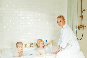 mother washing kids in bathtub