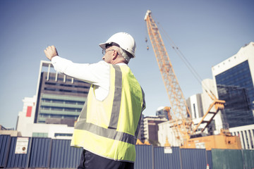 Senior foreman in glasses doing his job at building area on sunn