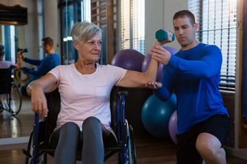 Male physiotherapist helping patient in performing exercise with