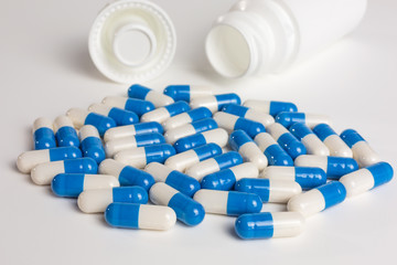 prescription medicine - blue and white capsules on white background with bottle