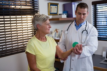 Physiotherapist assisting senior woman with stress ball exercise
