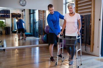 Physiotherapist assisting senior woman patient to walk with