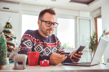 Men holding credit card and using laptop at home office