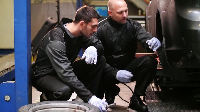 auto mechanics changing car tires at workshop