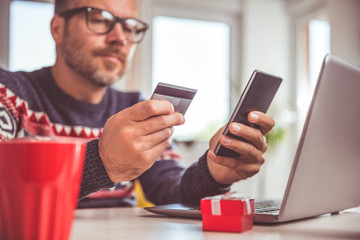 Men holding credit card and using smart phone at home office