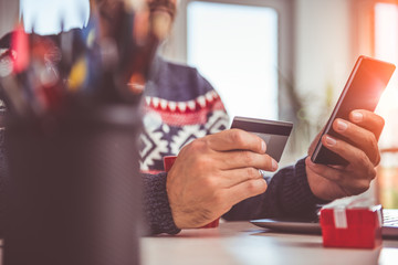 Men holding credit card and using smart phone at home office