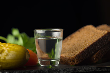 a glass of vodka, bread, tomatoes