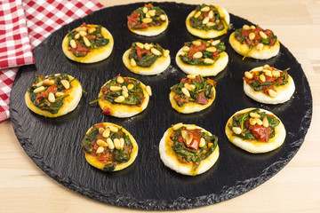 mini pizzas with tomato, spinach and pine nuts