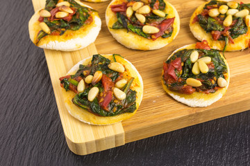 mini pizzas with tomato, spinach and pine nuts