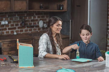 Mother and son painting birdhouse