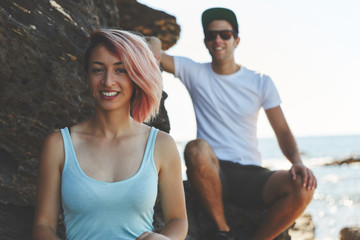 Obraz premium Young woman sitting on rock with friend smiling