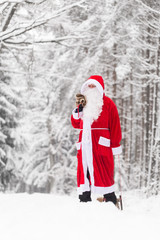 Weihnachtsmann trägt einen Sack mit Geschenken durch eine weiße Winterlandschaft