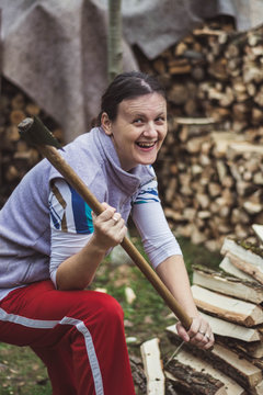 Happy young woman chopping wood in her backyard.