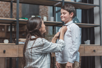 Mother tying necktie on son