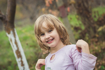 Young, blonde girl playing around in the backyard and smiling. 