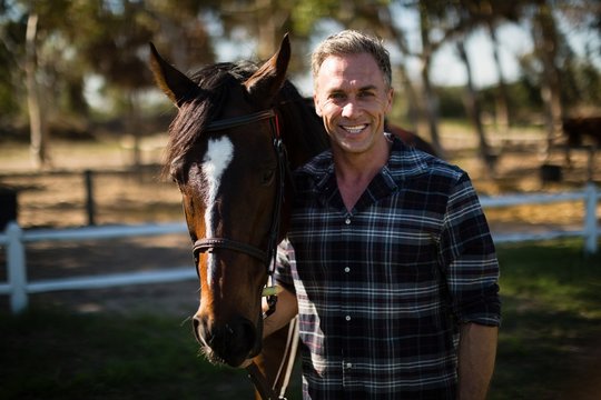 Man standing with horse in the ranch - Powered by Adobe