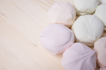 Multicolored marshmallow in the right side of the frame on a wooden background