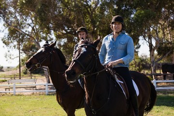 Two male friends riding horse in the ranch