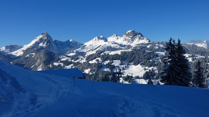 Fototapeta na wymiar View from the Hohe Wispile ski area, Gstaad. Snow covered mountains Gummfluh and Videmanette.
