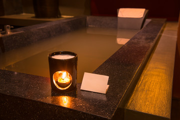 Aroma lamp with burning candle in bathroom