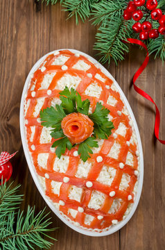Festive salad, decorated with salmon on a wooden table