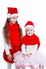Two charming girls in hats of Santa Claus. White background, isolated