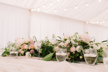 Wedding floral composition and candles in transparent candlesticks