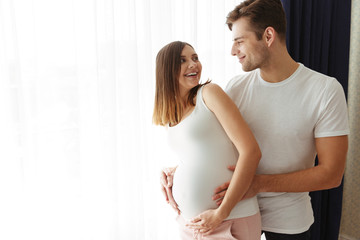 Happy man hug his lovely pregnant wife indoors at home