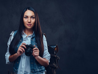 A woman with backpack holds compact photo camera.