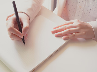 hands of asian business woman(30s to 40s) record on blank of account book by black pen with pink or pastel suits with soft focus background