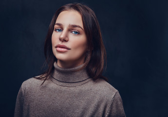 A woman dressed in a long neck brown jacket.