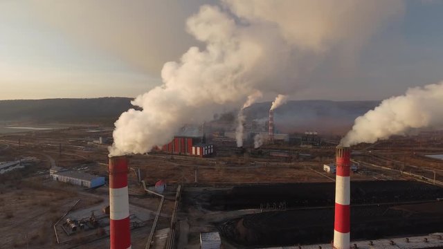 Metallurgical metal plant. Close Red tubes smoke power factory.
Industrial dark dirty landscape. Summer dramatic  morning. Aerial helicopter drone flight. 
